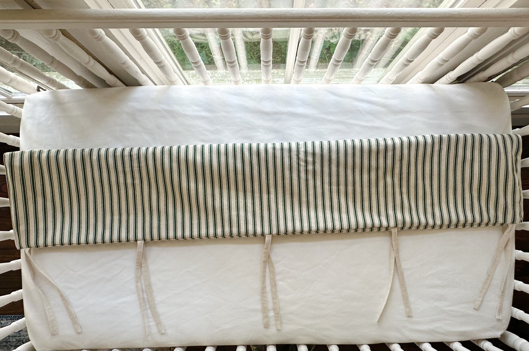 Looking down at the cover folded over the top rail, ties knotted loose against the white sheet