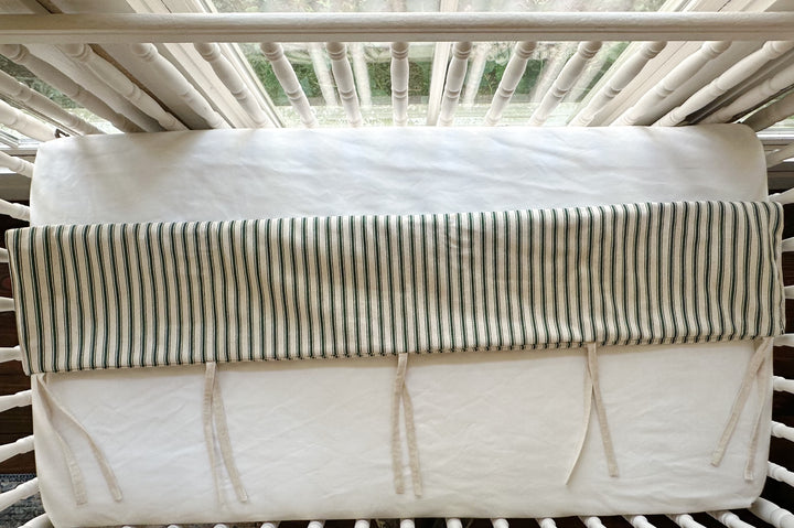 Looking down at the cover folded over the top rail, ties knotted loose against the white sheet