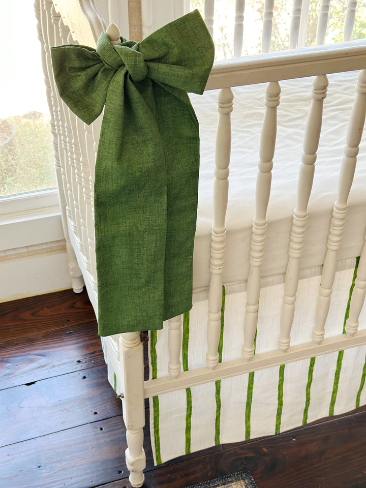 Green sash knotted over the corner finial, its tails hanging past the striped skirt