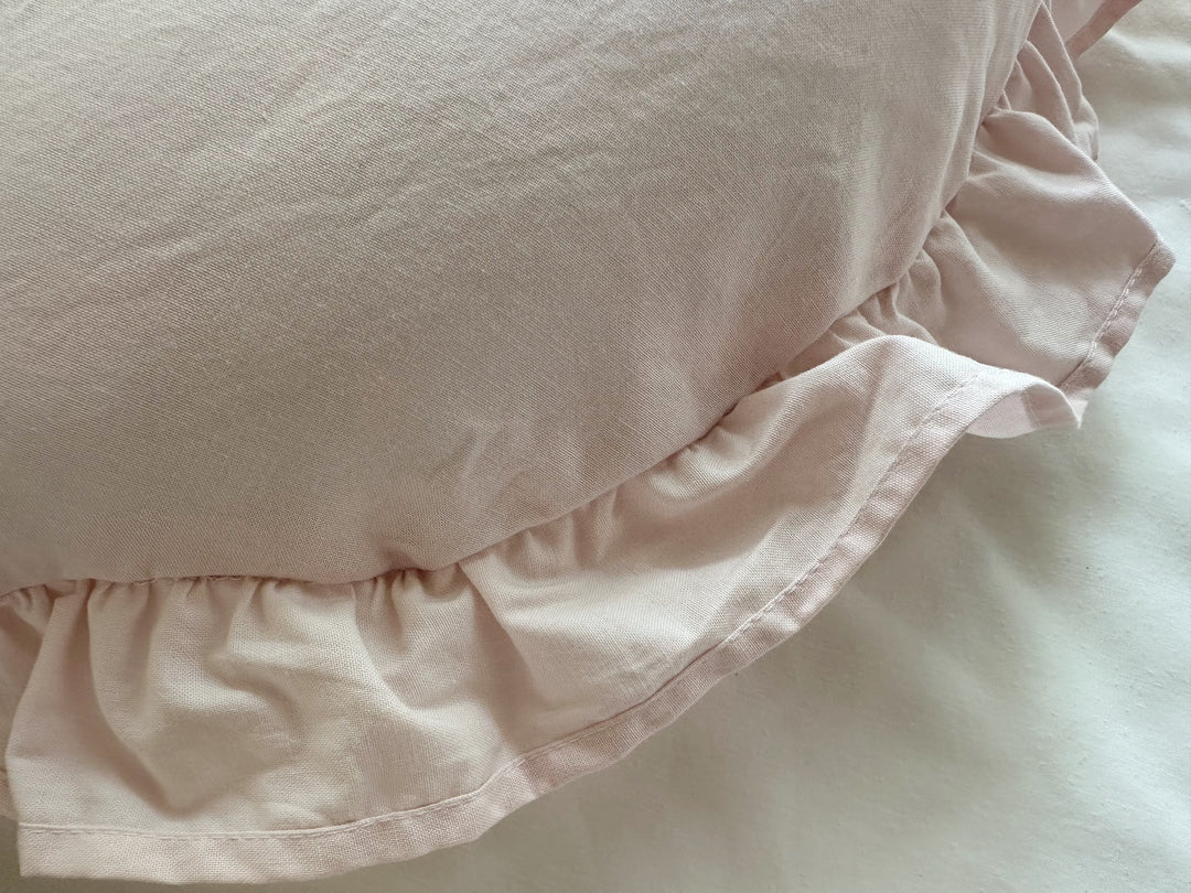 Close-up of the hand-gathered Baby Pink ruffle with a narrow stitched hem along the pillow edge