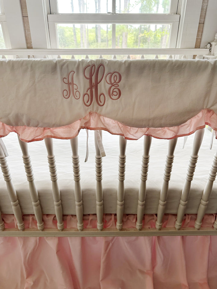 Monogrammed white scalloped crib rail cover with a Sisters Pink ruffle trim and white cotton ties
