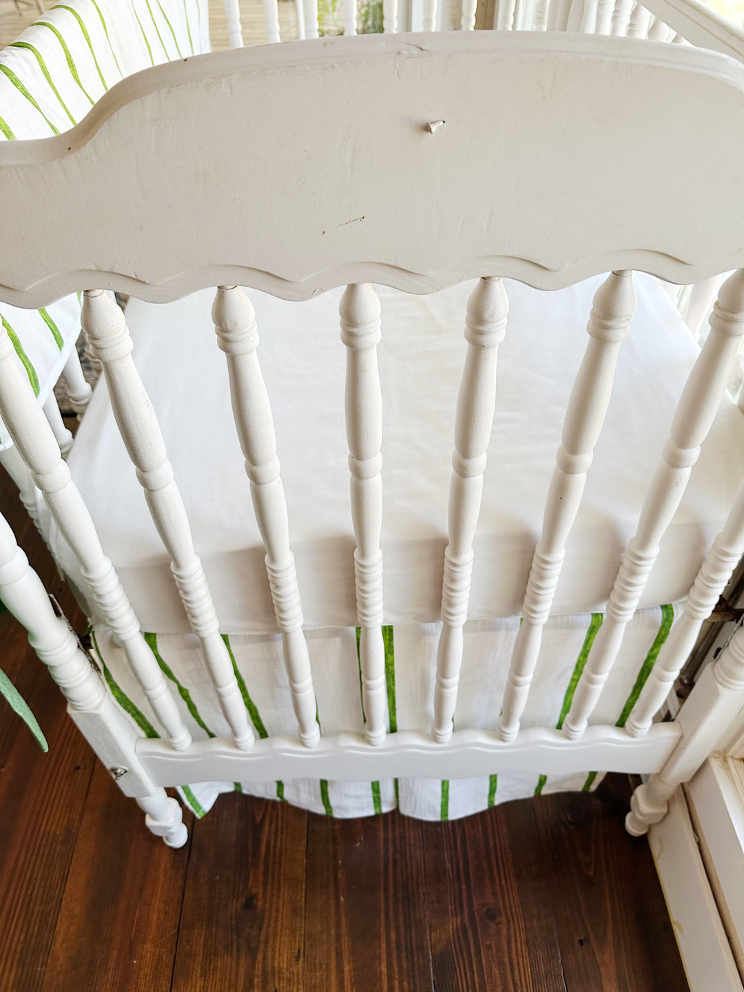 Close view of the scalloped headboard and turned spindles above the striped tailored skirt