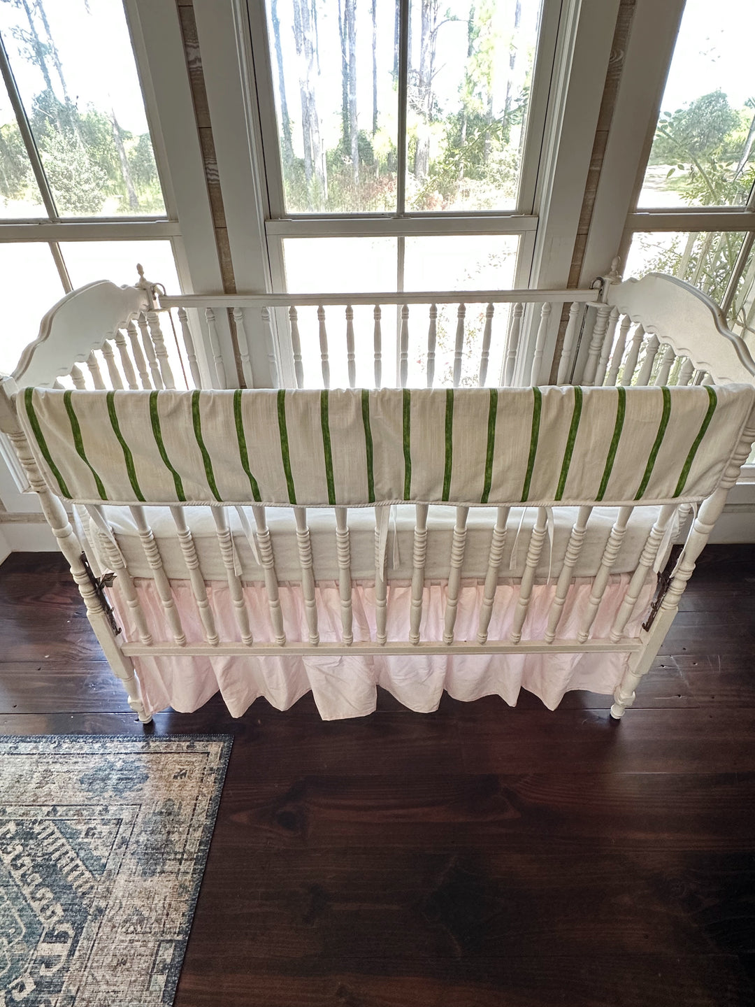 Overhead view of the whole crib showing the green stripe above the gathered pink skirt