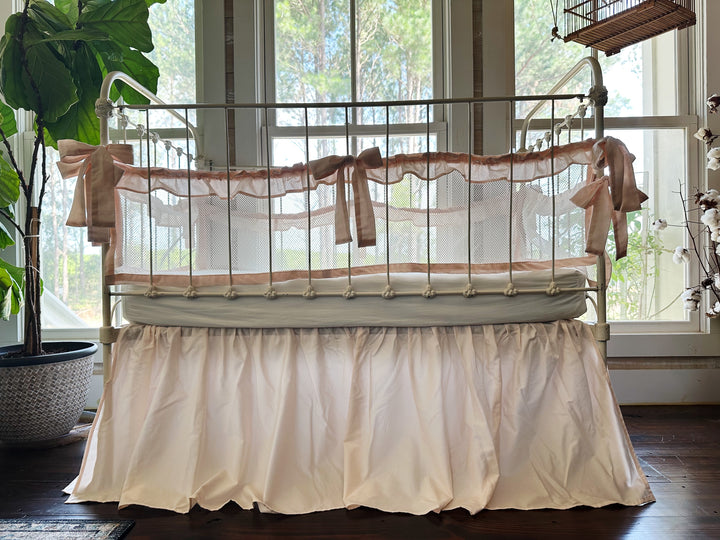Full crib view with farmhouse ruffled mesh crib liners and gathered crib skirt in ballet slipper pink, styled in a nursery