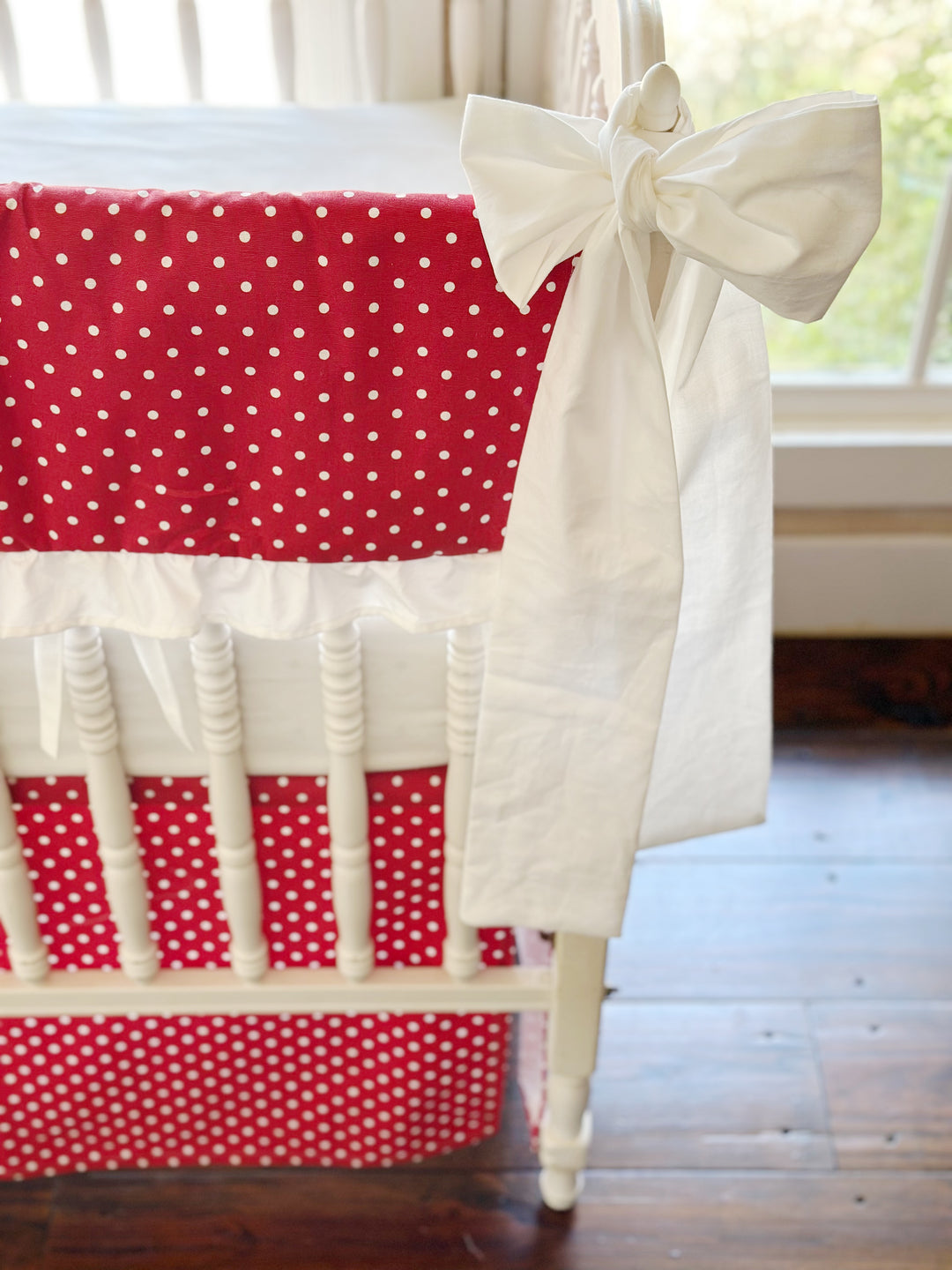 Close view of the small white dots on cherry red, the gathered white ruffle and a white sash