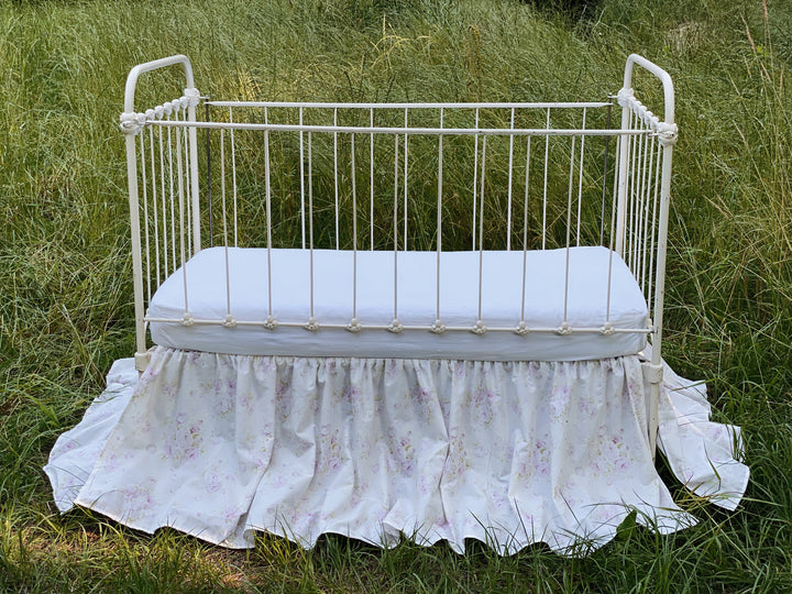Lavender shabby chic floral gathered crib skirt on antique iron crib in field
