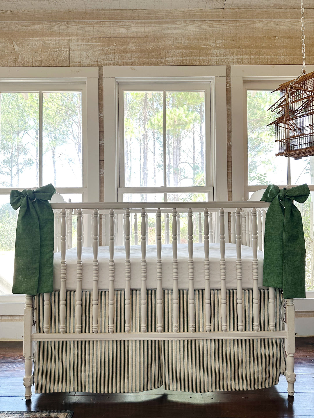 The ticking skirt and both green sashes seen straight on, pine-paneled wall and three windows behind