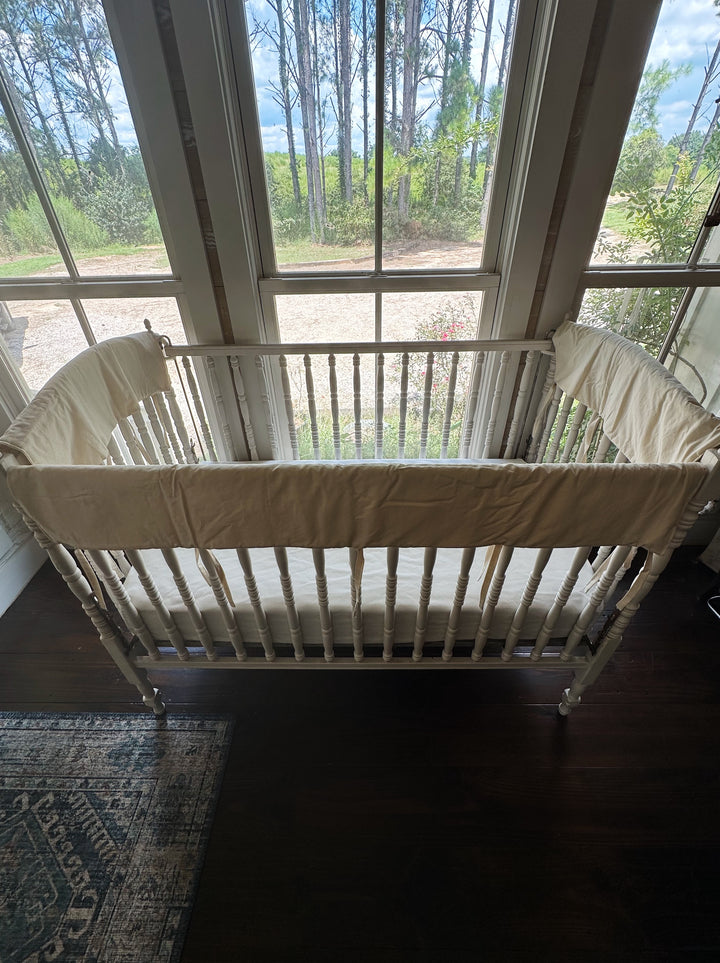 Full crib set of Natural crib rail covers on the long and short top rails of a white wooden crib