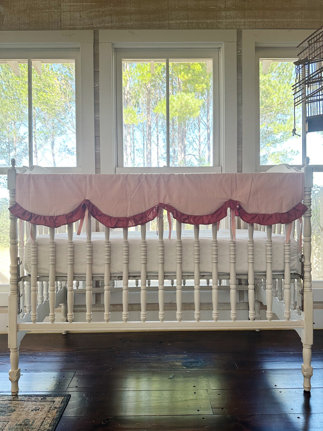 Sisters Pink scalloped crib rail cover with a deep blush ruffle on the front rail of a white spindle crib