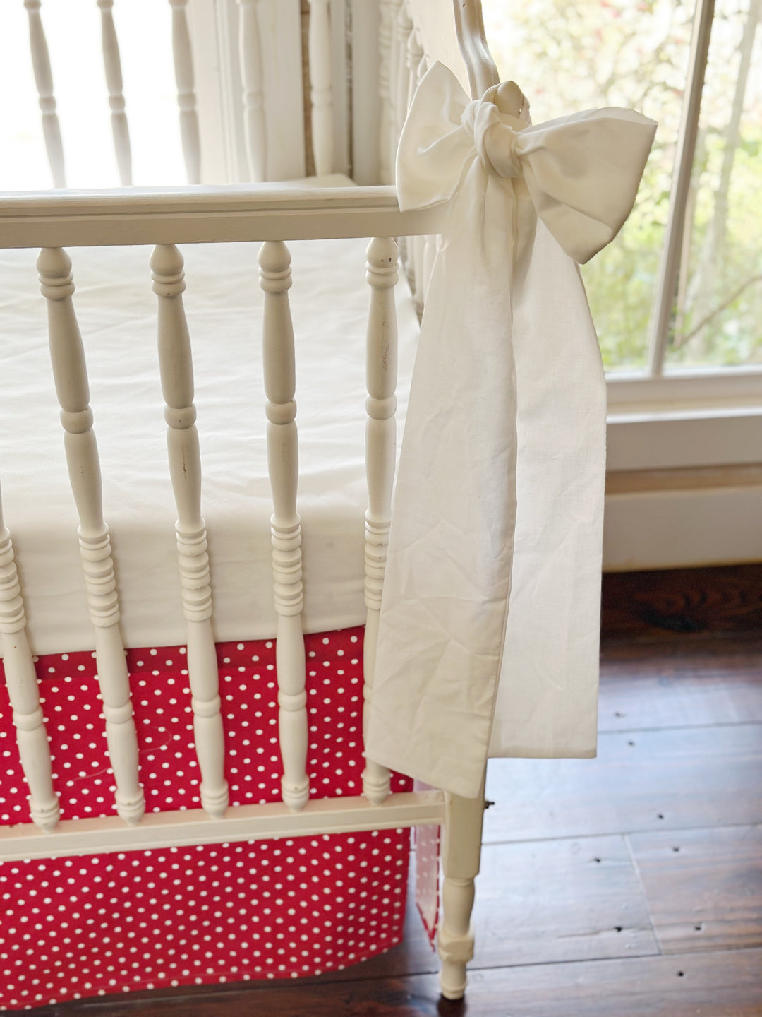 Tight crop of the bow's long tails with the dotted skirt and white crib sheet behind