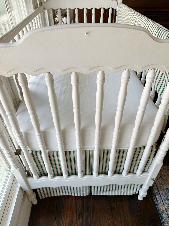 Turned spindles and the end of the crib, the ticking skirt's center pleat below