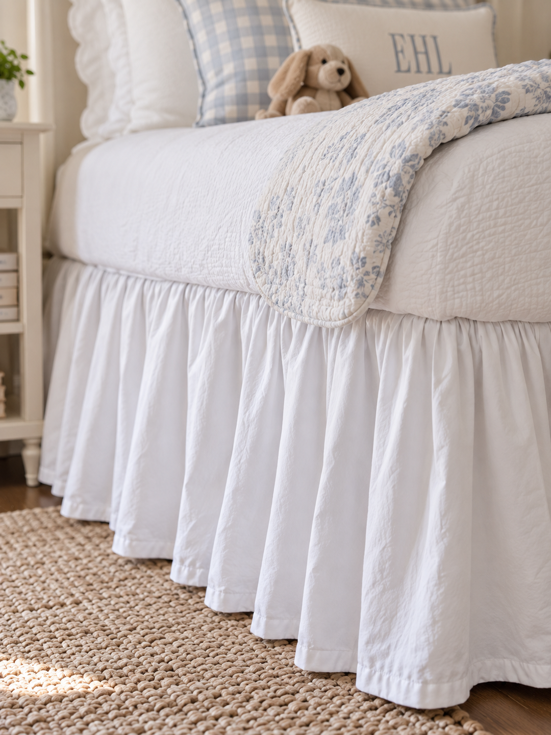 Close up of the gathered white farmhouse twin bed skirt falling to a jute rug - High Cotton Textile
