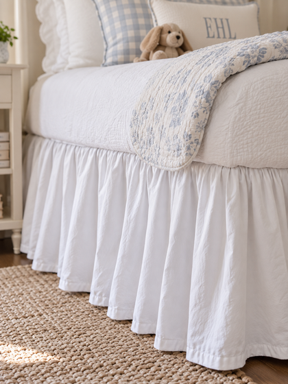 Close up of the gathered white farmhouse twin bed skirt falling to a jute rug - High Cotton Textile