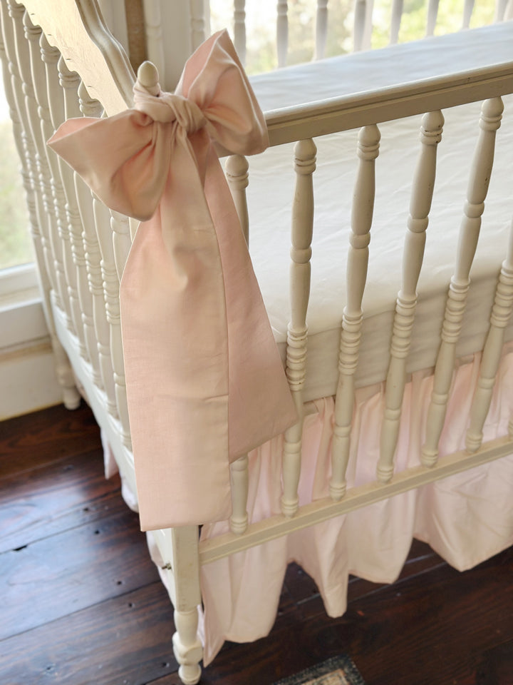 Close view of a baby pink sash knotted over the corner finial, its long tails hanging down