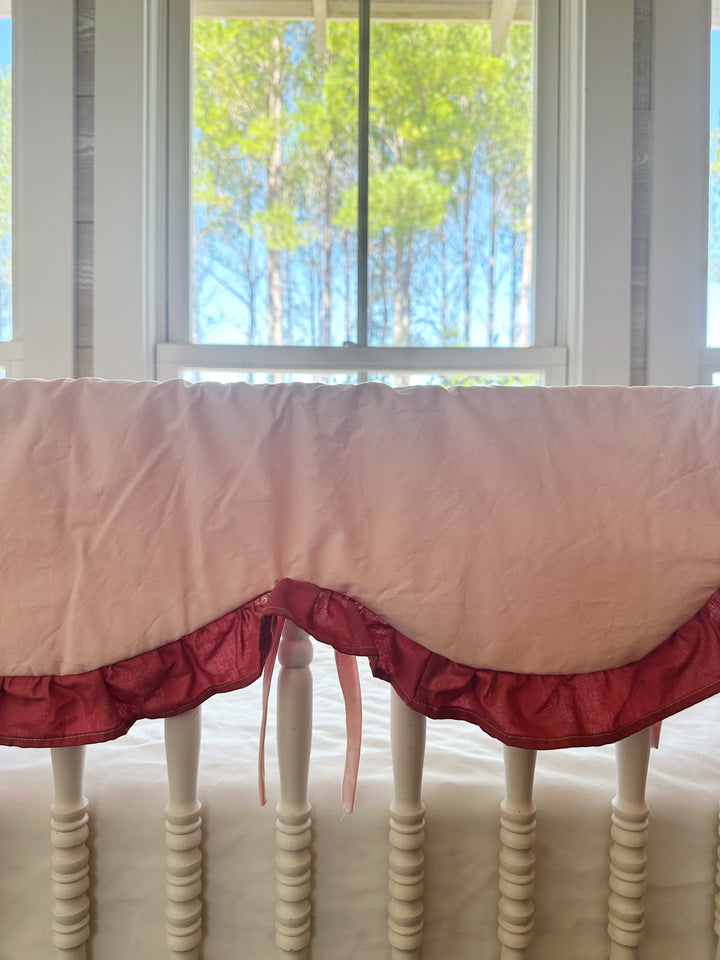 Close-up of one scallop, the Blush ruffle and a pink tie looped around a crib spindle