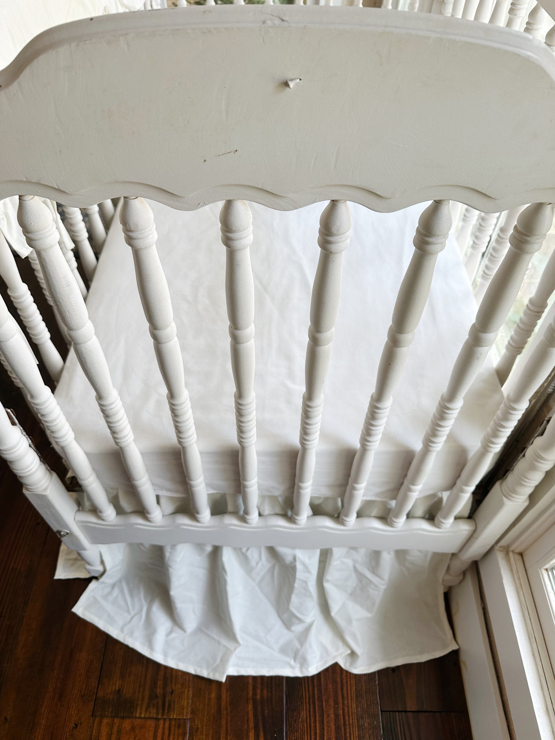 Wide nursery view of the porcelain set on the crib with a hanging birdcage to the right
