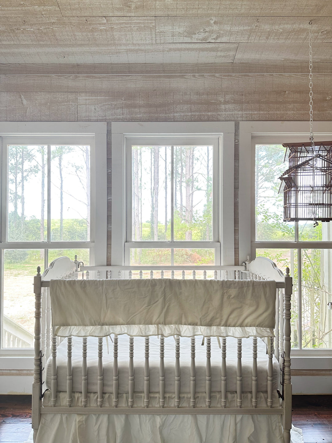Wide nursery view of the porcelain rail cover on the crib in a pine-panelled room