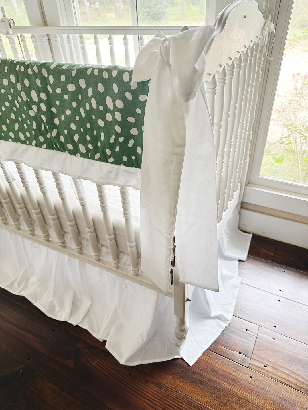Side view of the dot print running the length of the long crib rail above the white skirt