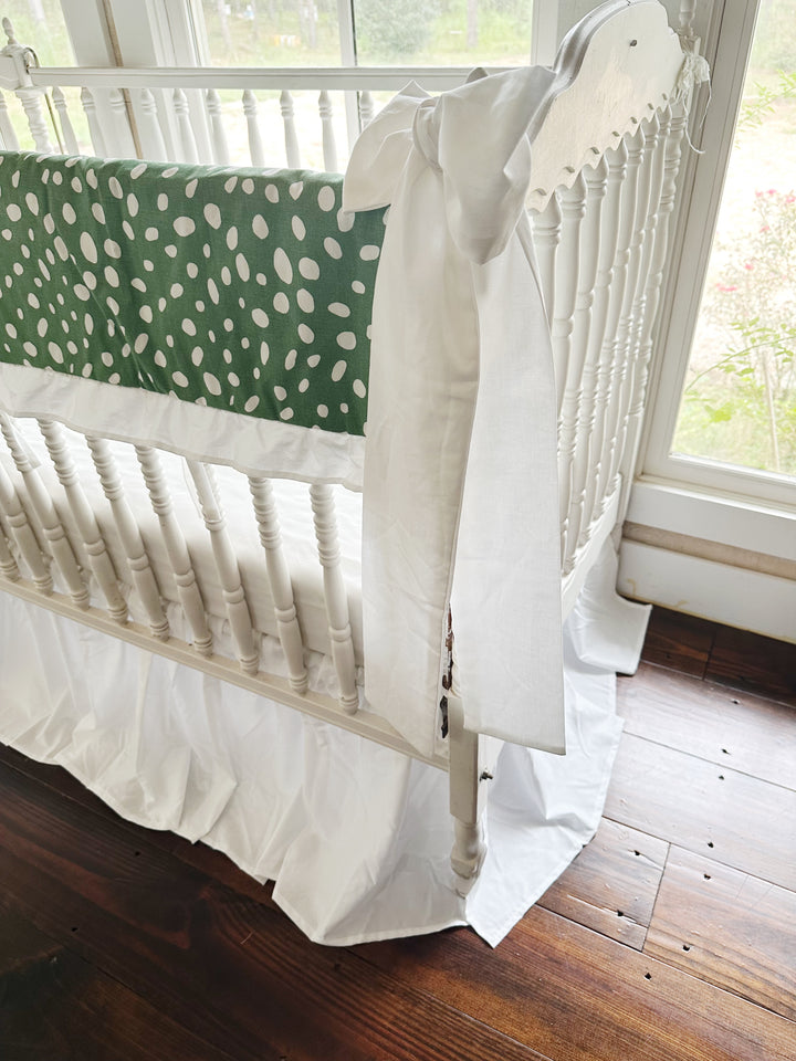Side view of the dot print running the length of the long crib rail above the white skirt