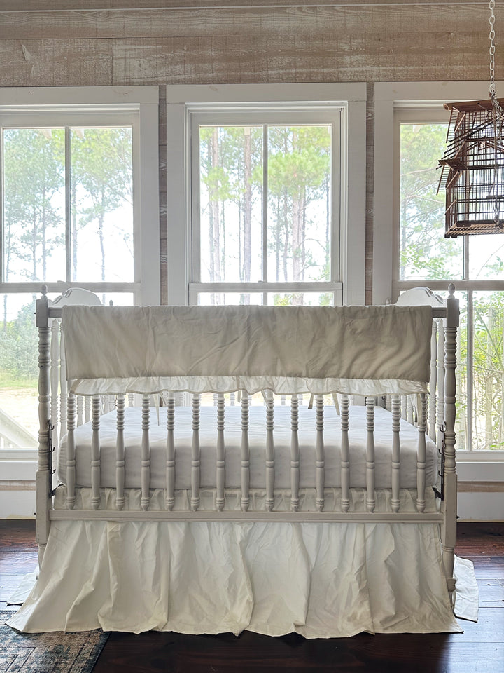 End view of the crib showing the porcelain skirt hem against dark wood floors