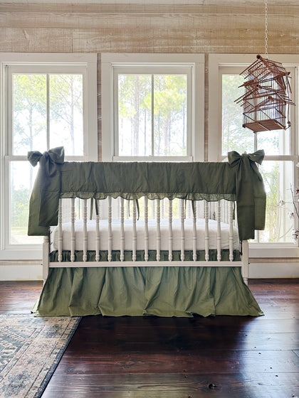 Pine green gingham crib rail cover, farmhouse skirt and two large bows on a white spindle crib