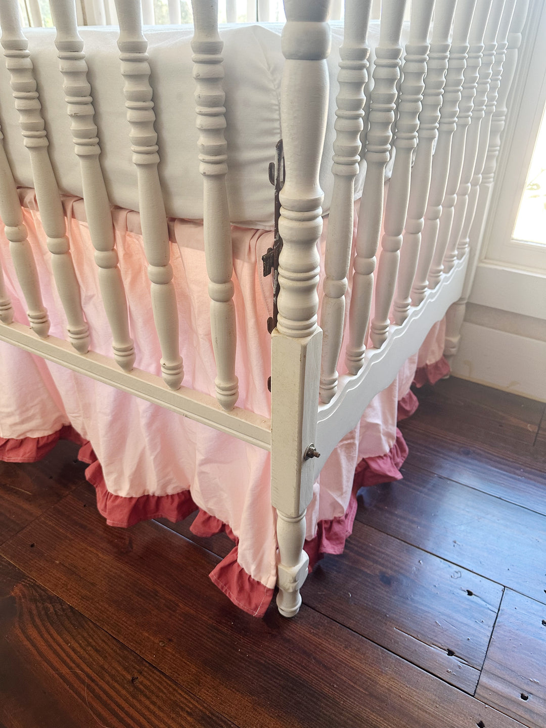 Low view of the crib corner, Sisters Pink skirt gathered evenly around the post with blush ruffle at the hem