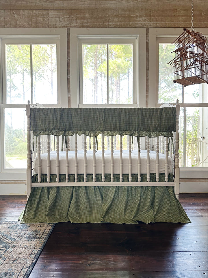 Green gingham crib rail cover and crib skirt set in a farmhouse nursery with pine tree views