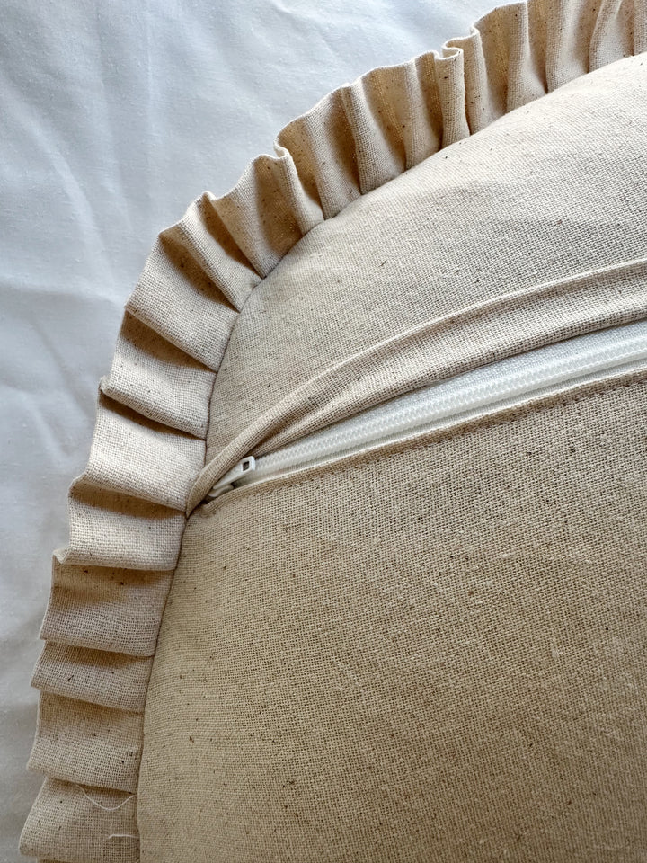 Envelope flap lifted to show the hidden white zipper on the back of the Natural Osnaburg Boppy pillow cover