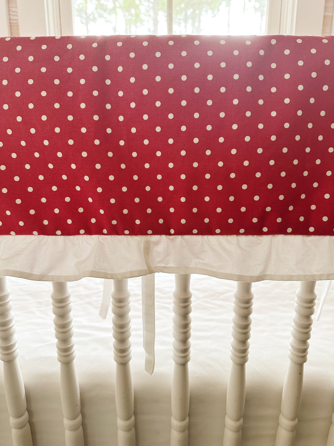 Close view of the small white dots on deep cherry red cotton above the gathered white ruffle
