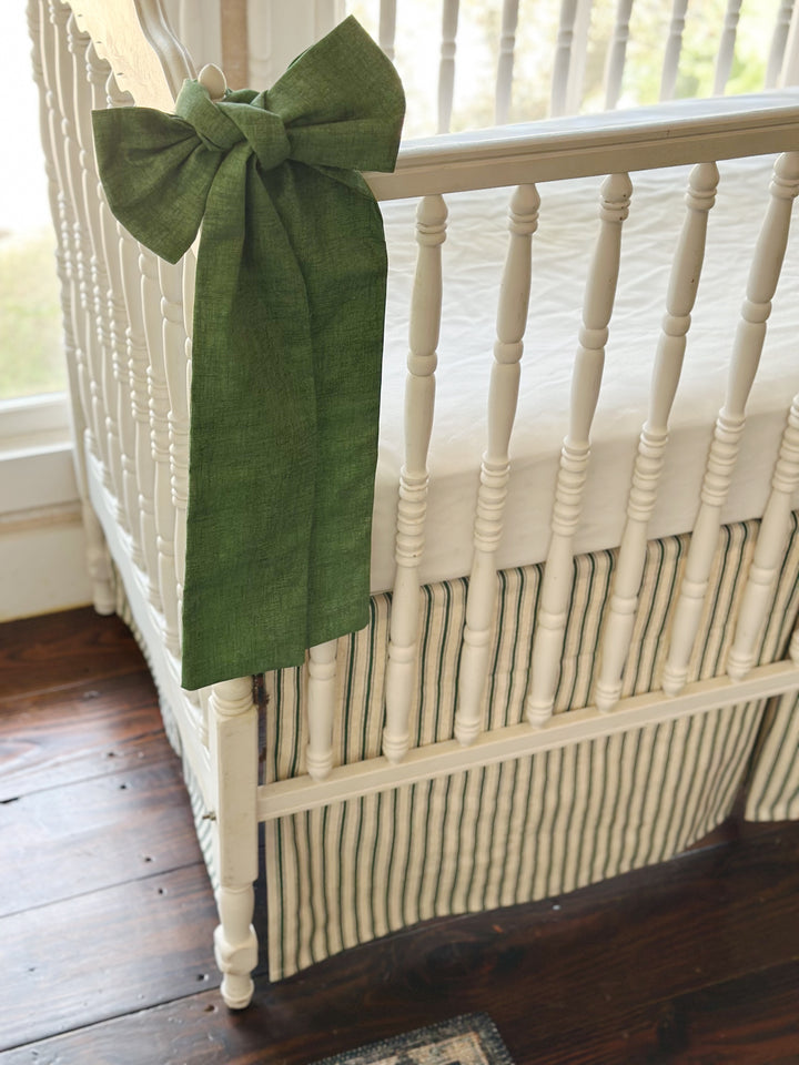 Close view of a cypress green sash knotted at the corner post with the ticking skirt below