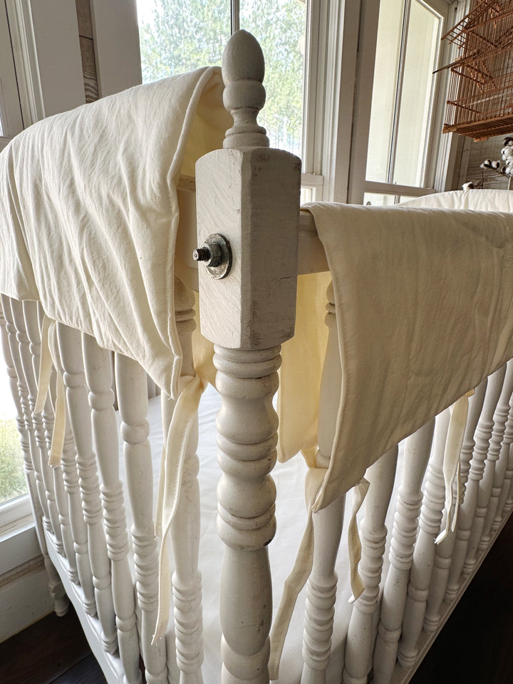 Ivory rail covers meeting at the crib corner post beside the turned wooden finial