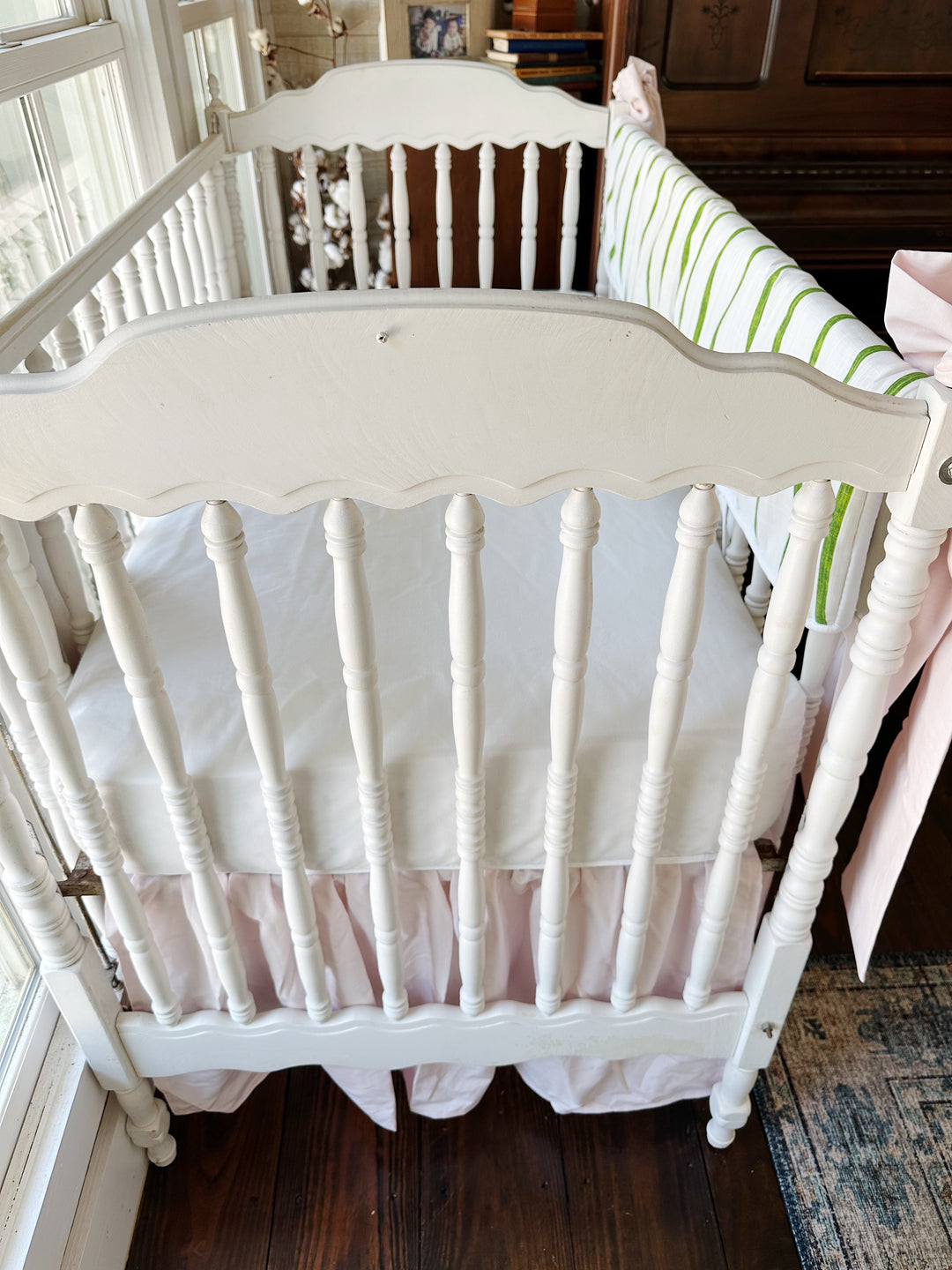 Looking down at the head of the crib past the scalloped headboard to the pink gathered skirt