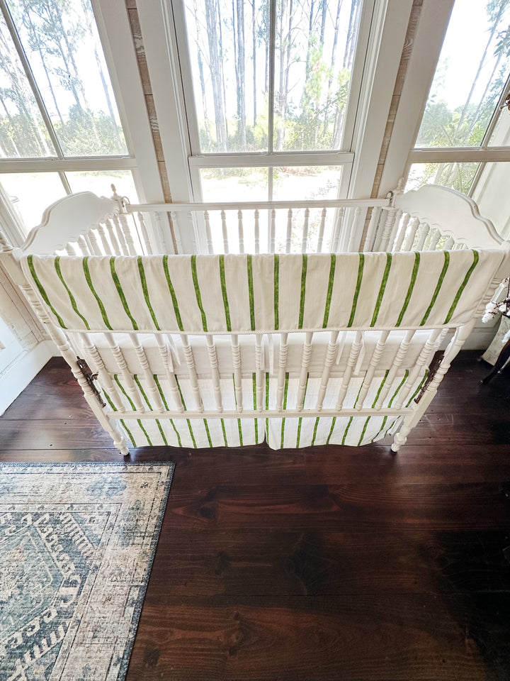 Overhead view of the whole crib showing the striped rail cover and the striped skirt below