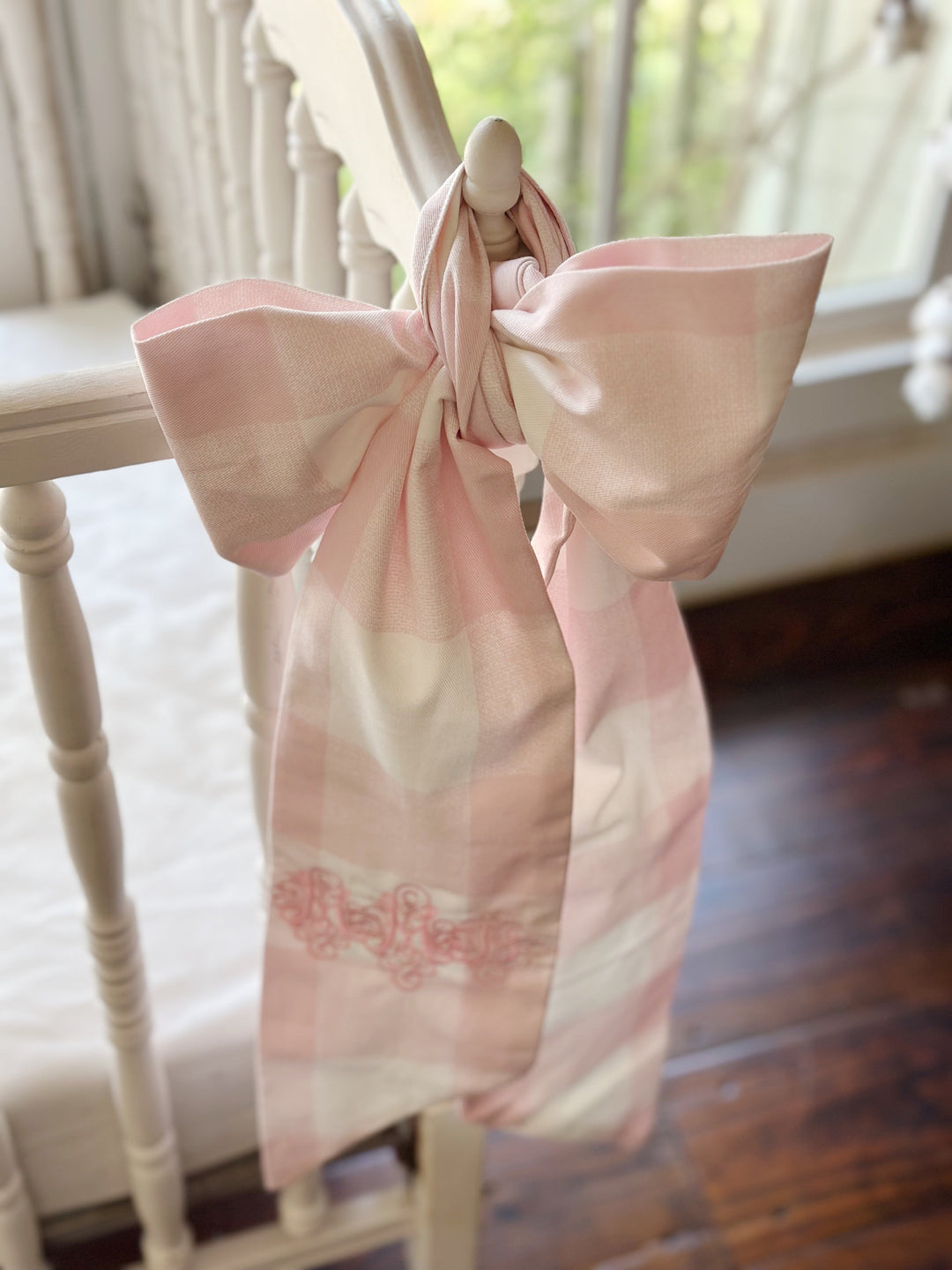 Backlit view of the tied bow with the pink check softened by window light