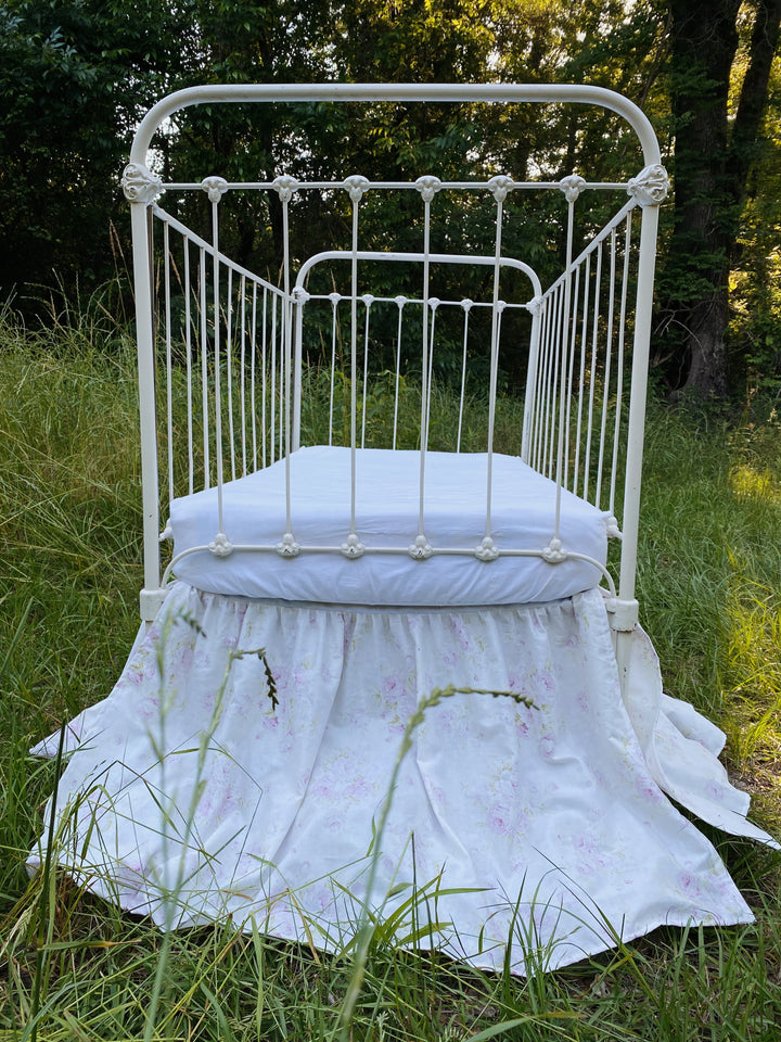 Lavender rose floral crib skirt end view on antique iron crib outdoors