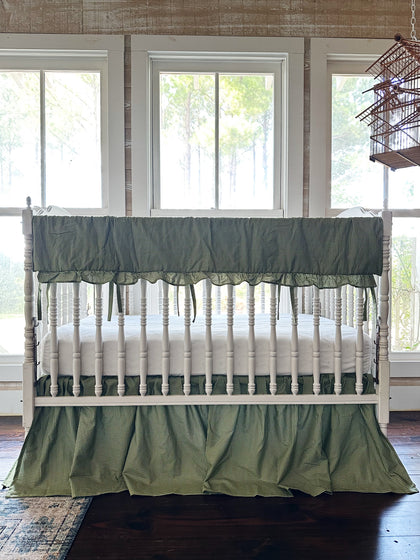 Pine green gingham crib rail cover and farmhouse crib skirt on a white spindle crib