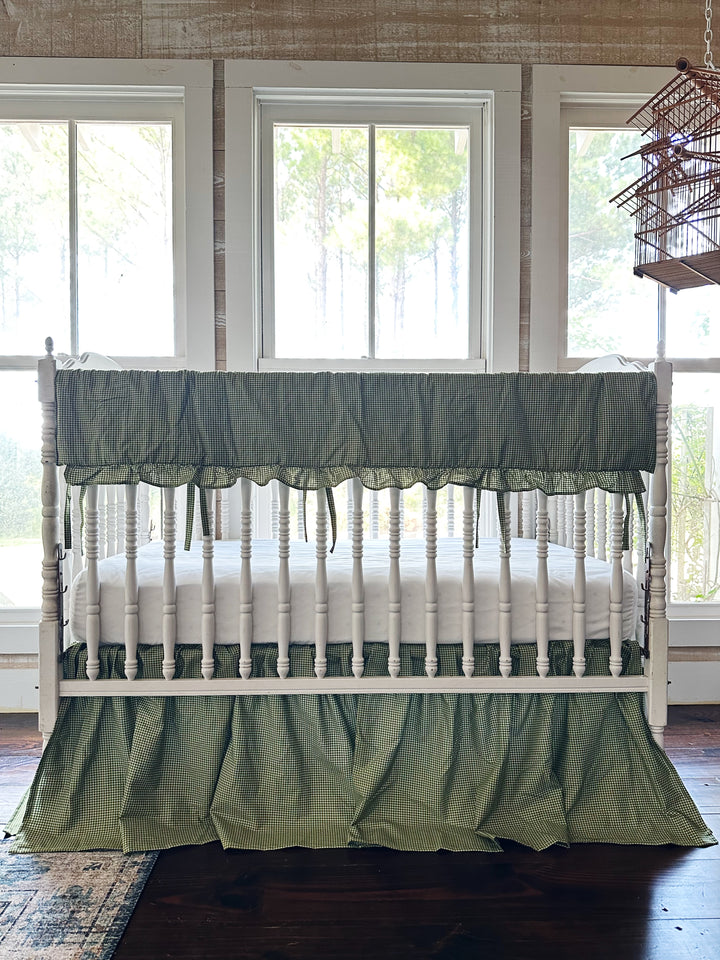 Pine green gingham crib rail cover and farmhouse crib skirt on a white spindle crib