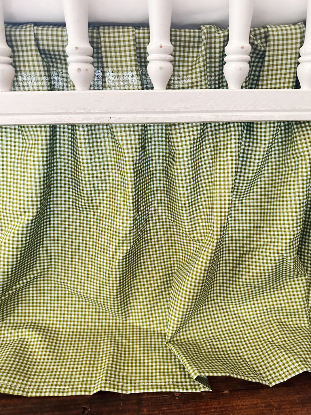 Gathered pleats and hemline of the green gingham farmhouse crib skirt
