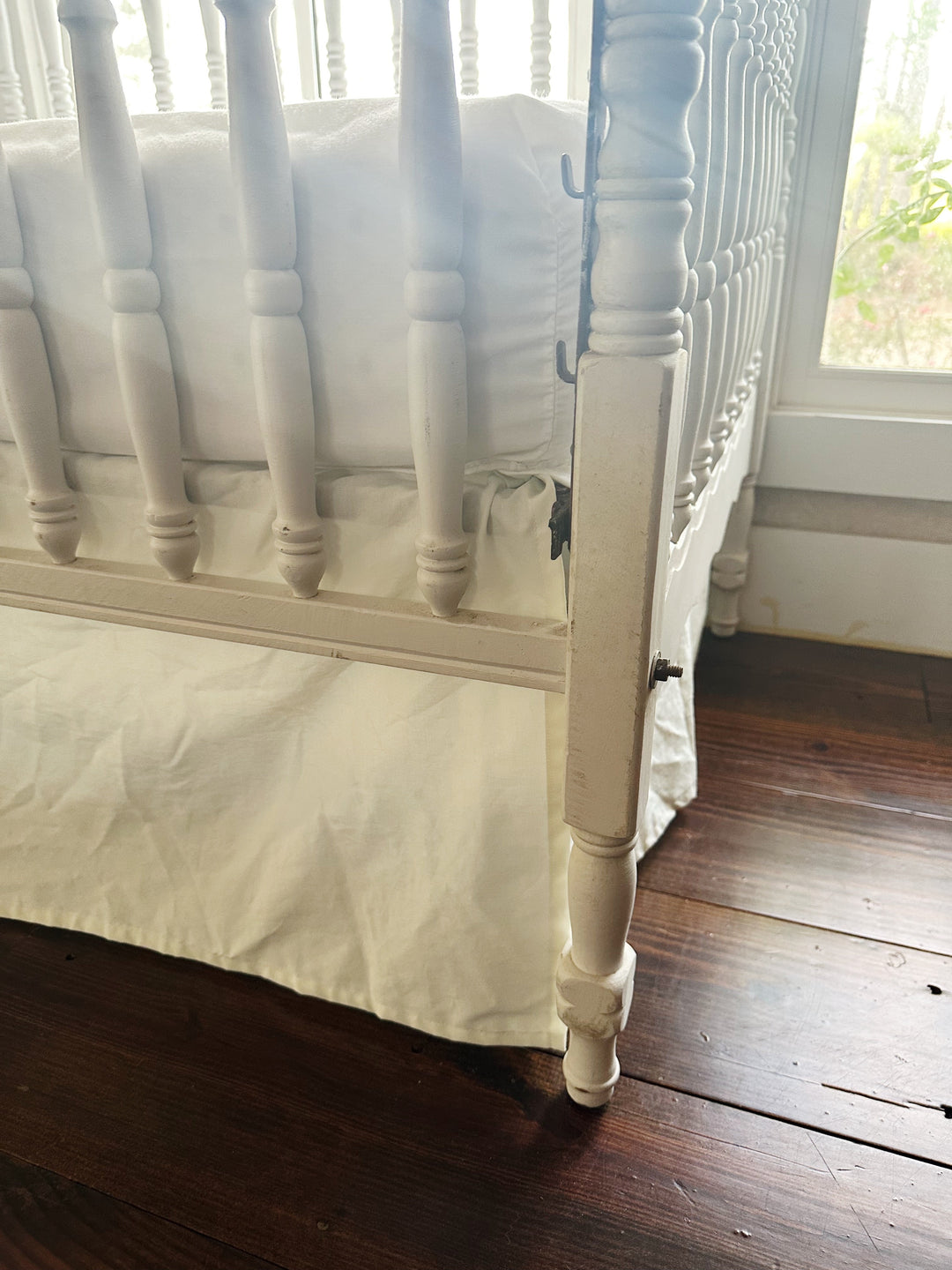 Split corner of the porcelain crib skirt wrapping cleanly around a turned crib leg - High Cotton Textile