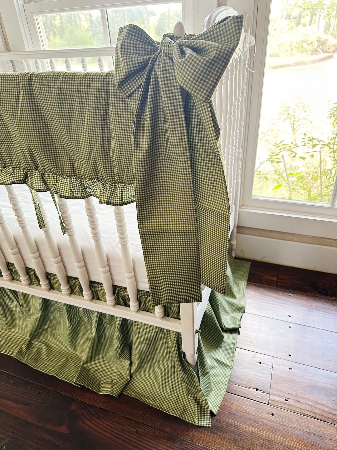 Large green gingham crib bow hand-tied at the corner post of a white crib