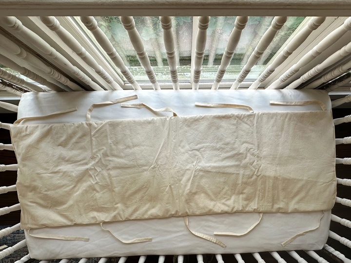 Long Natural crib rail cover shown flat with soft ties along the bottom edge