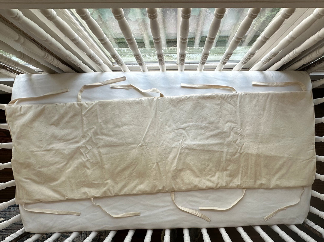Handmade Natural crib rail cover laid open to show its full 52 inch length and ties