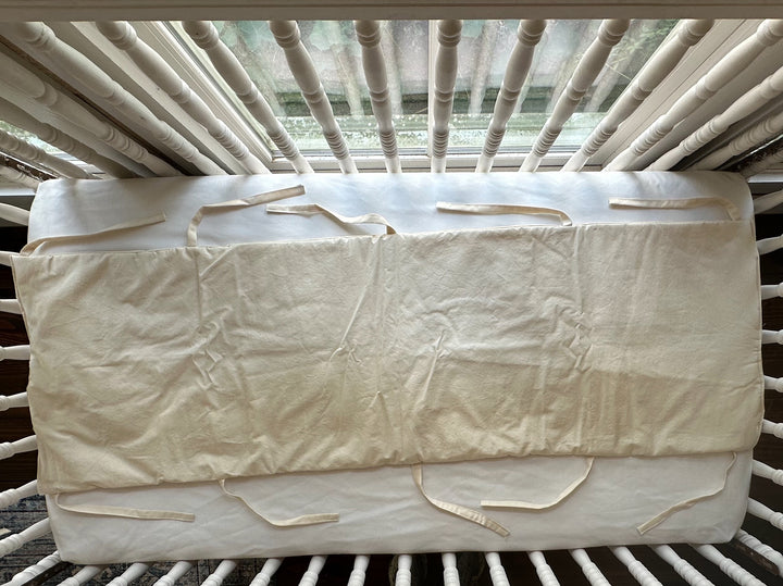 Handmade Natural crib rail cover laid open to show its full 52 inch length and ties