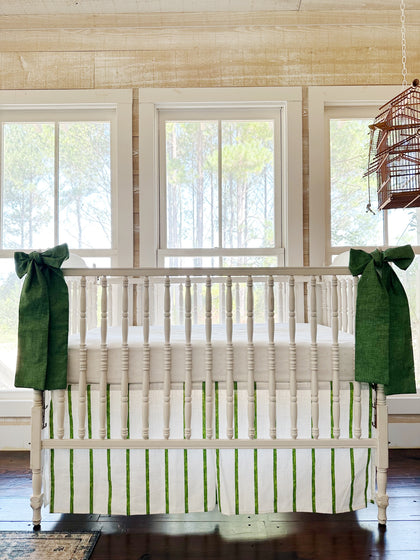 Cypress green and white striped tailored crib skirt with two solid green sashes tied to the front posts