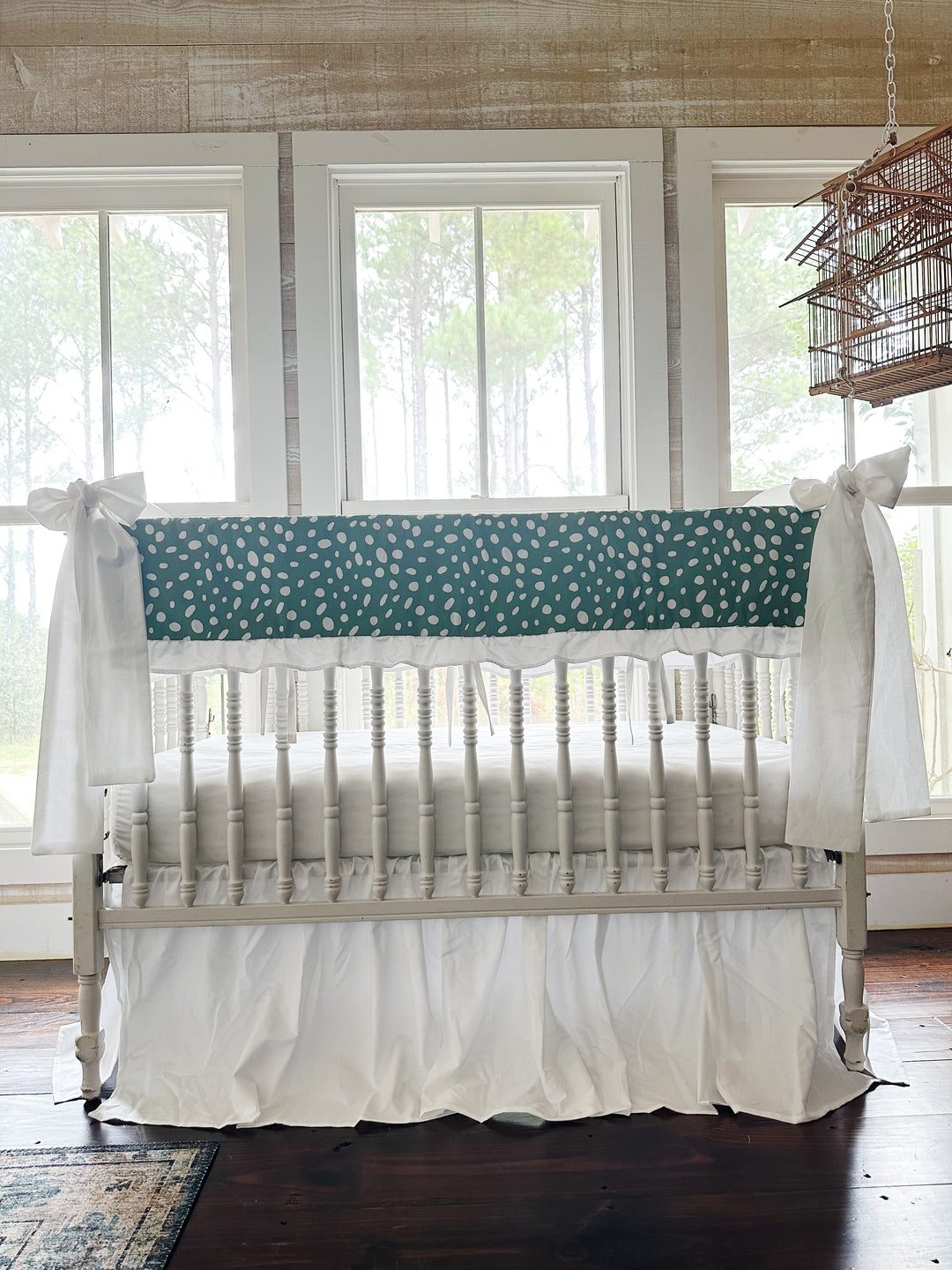Straight-on view of the green dot crib set with both white bows on the front posts