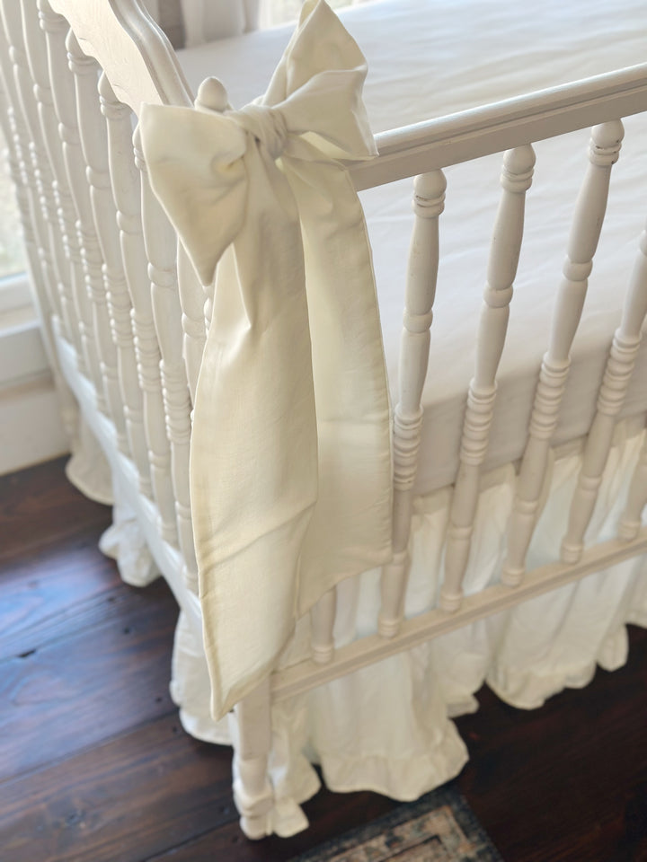 Porcelain bow tied at the corner post above the scalloped end rail, ruffled skirt gathered to the floor below