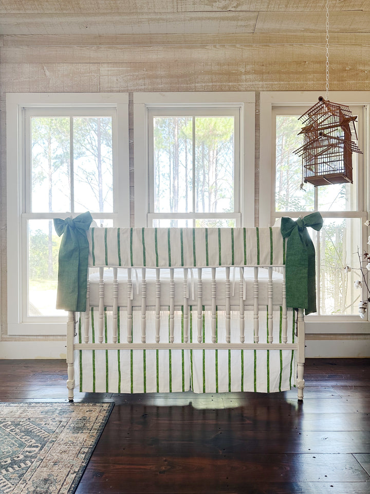 The striped crib set across a pine-paneled room with three tall windows and a hanging birdcage