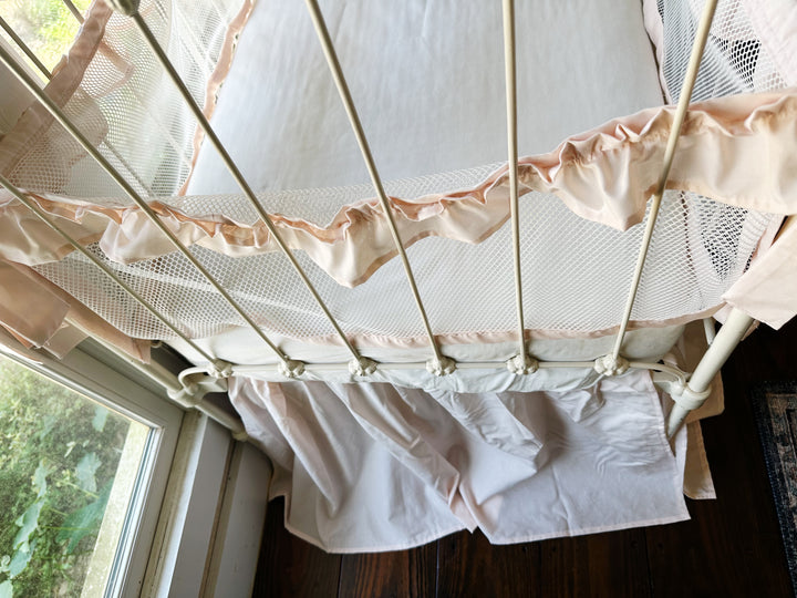 Side view of crib with full bedding set, showing liners tied to crib rails and skirt flowing around base