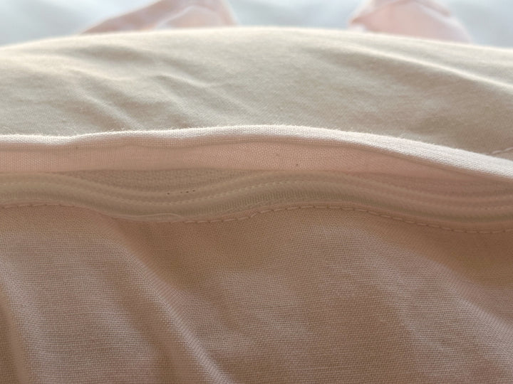 Envelope flap turned back to show the zipper hidden inside the Baby Pink Boppy pillow cover
