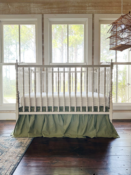 Green gingham gathered crib skirt on a white spindle crib in a farmhouse nursery